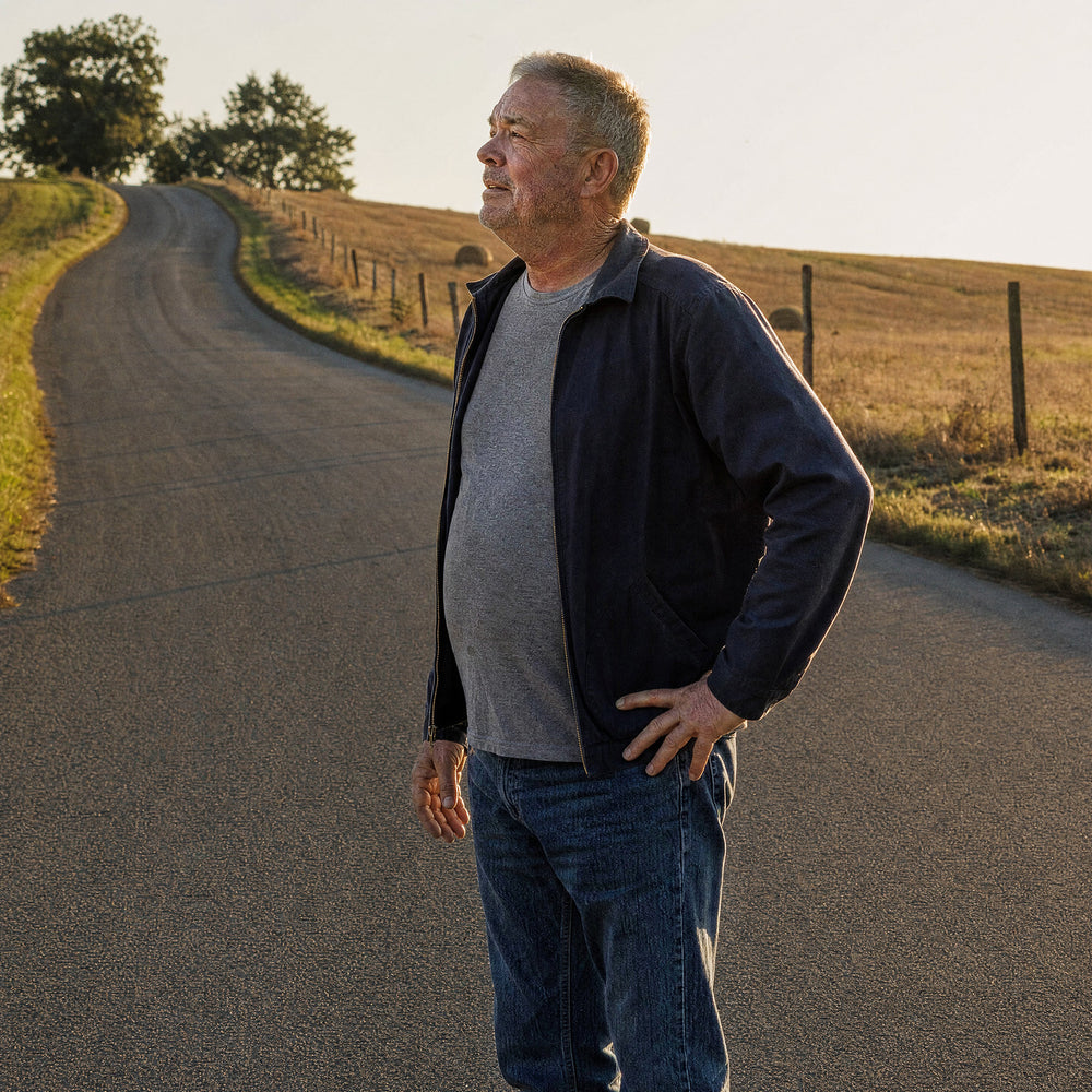 A man in his sixties stopping to catch his breath partway up a country road
