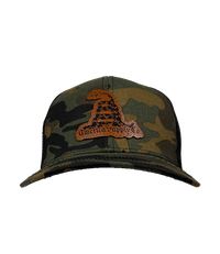 The Alex Jones Store - Front view of camo America Supply Co Gadsden leather patch trucker hat with coiled rattlesnake design on black mesh