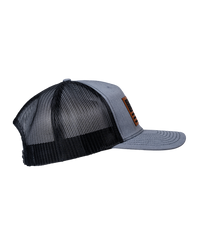 The Alex Jones Store - Heather grey and black trucker hat, right side view, featuring leather American flag patch on the front panel