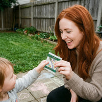 Mother and toddler sharing Kids Greens Gummies outdoors
