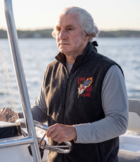 Live Free Or Die Full-Zip Fleece Vest in black, worn at the helm on the water