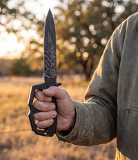 The Alex Jones Store - Molon Labe Trench War Dagger held in hand at a Texas ranch fence line